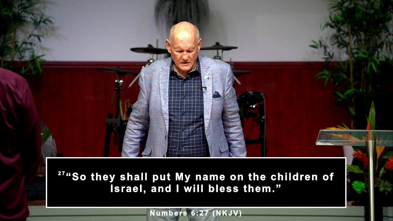 A speaker on stage at CoastWIDE Church with Numbers 6:27 on screen during the Sunday evening service