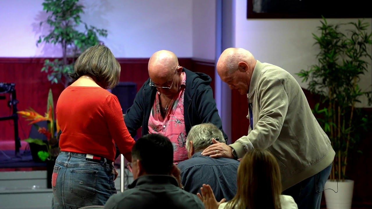 Leaders praying with people at the front of the auditorium during a Sunday service at CoastWIDE Church