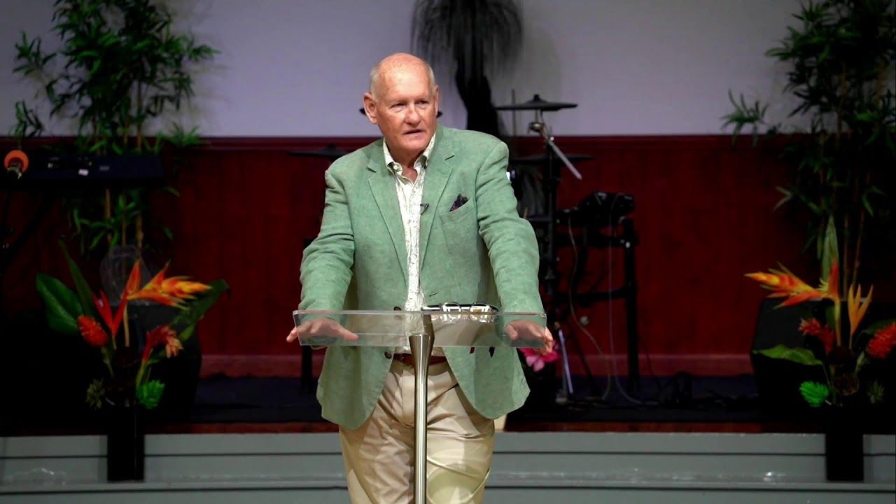 A speaker in a green jacket preaching at the glass lectern during the Sunday morning service at CoastWIDE Church, Arundel