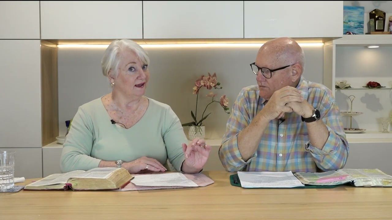Susan Cunningham speaking beside Shayne Cunningham, their Bibles open on the table