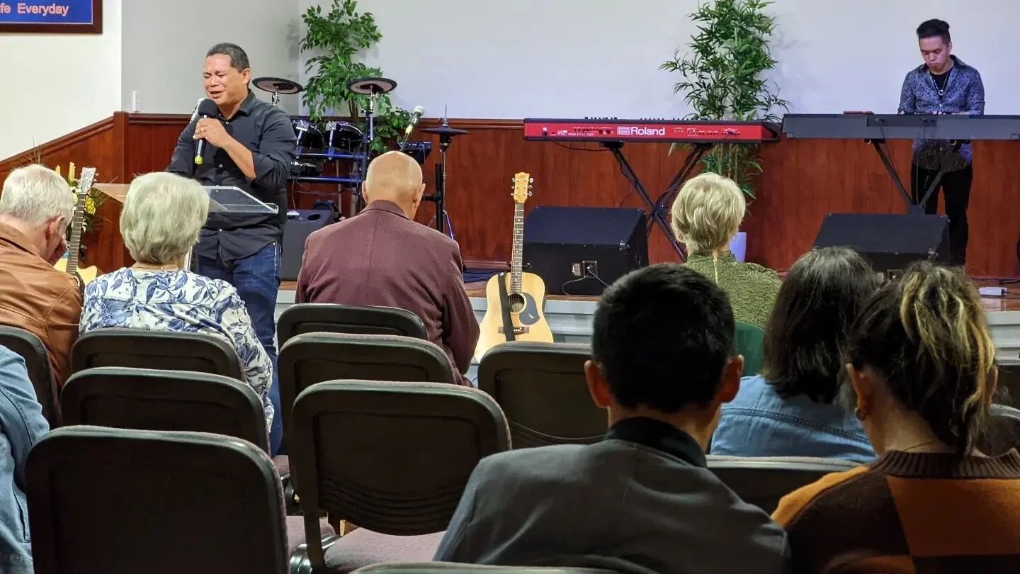 Pastor Herane Suralta leads Sunday worship beside the band at CoastWIDE Church in Arundel as the congregation looks on
