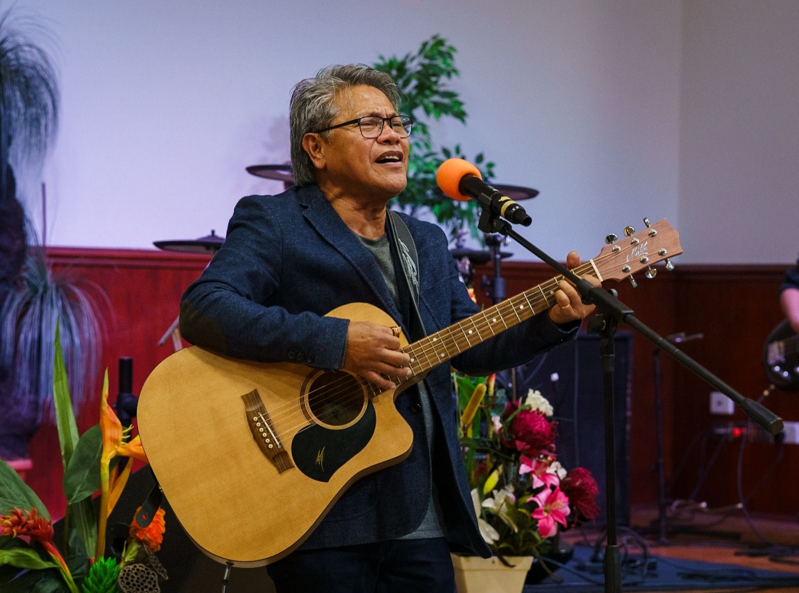 Worship Director Joel Gonzales singing with an acoustic guitar at CoastWIDE Church