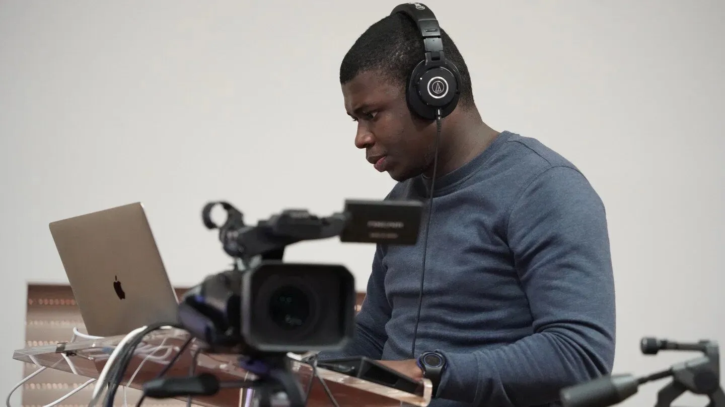 A livestream operator in headphones at a camera and laptop during a CoastWIDE Church service