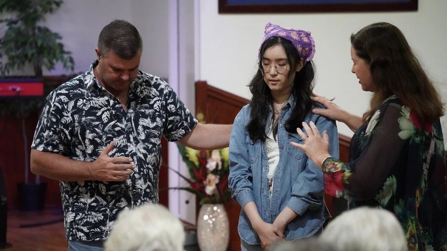Two people lay hands on a young woman and pray for her at CoastWIDE Church
