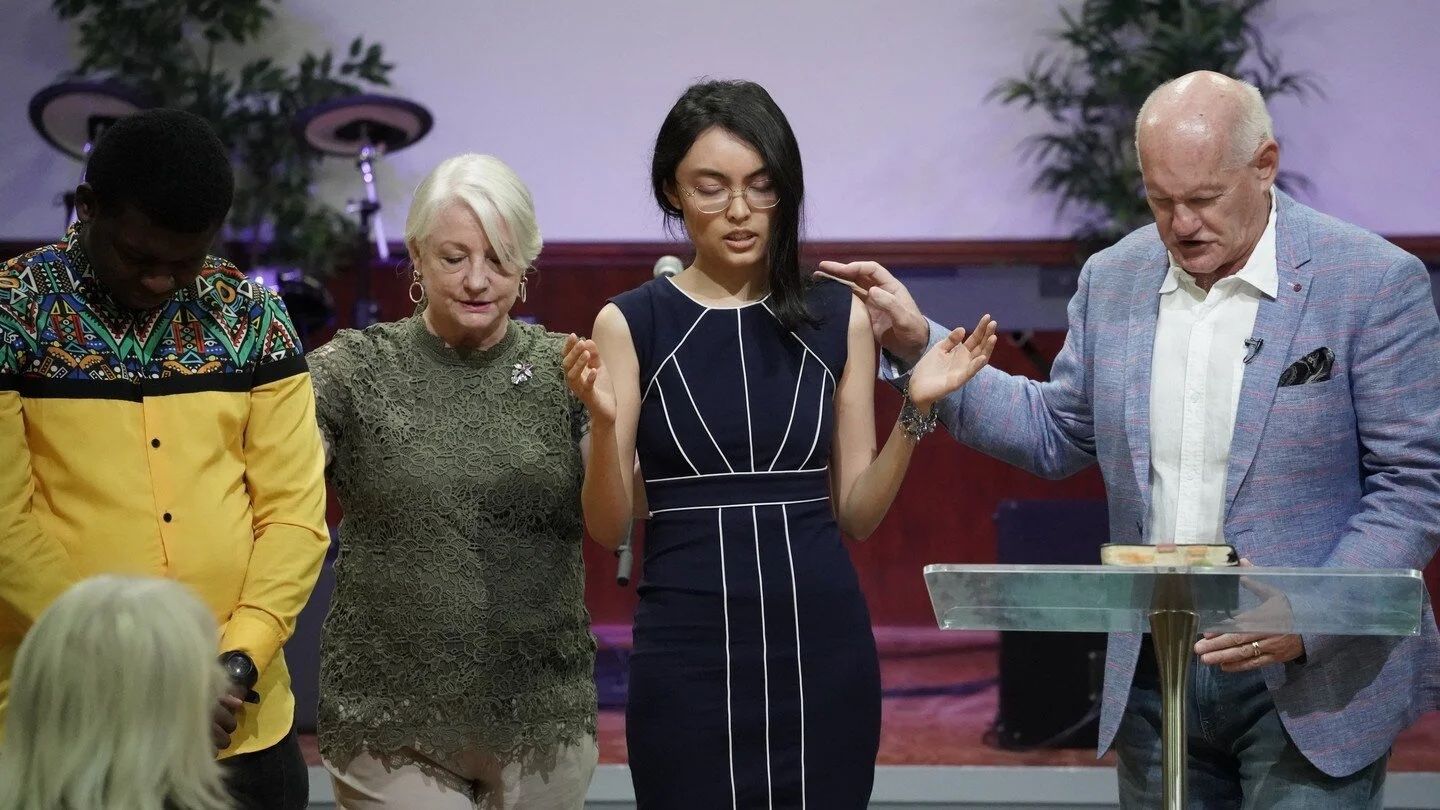 Pastors Shayne and Susan Cunningham and leaders pray for a student at the front of CoastWIDE Church