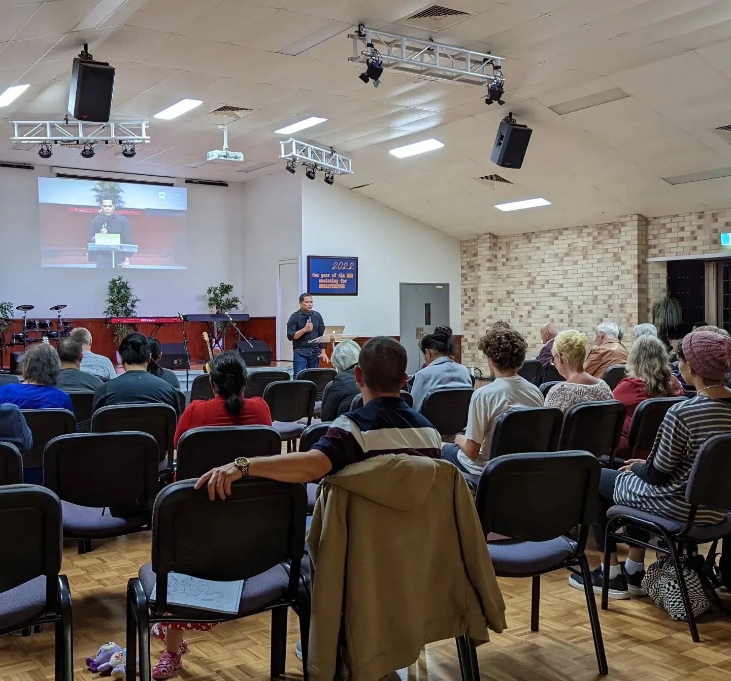 A full room at a Sunday evening meeting, with a speaker at the front