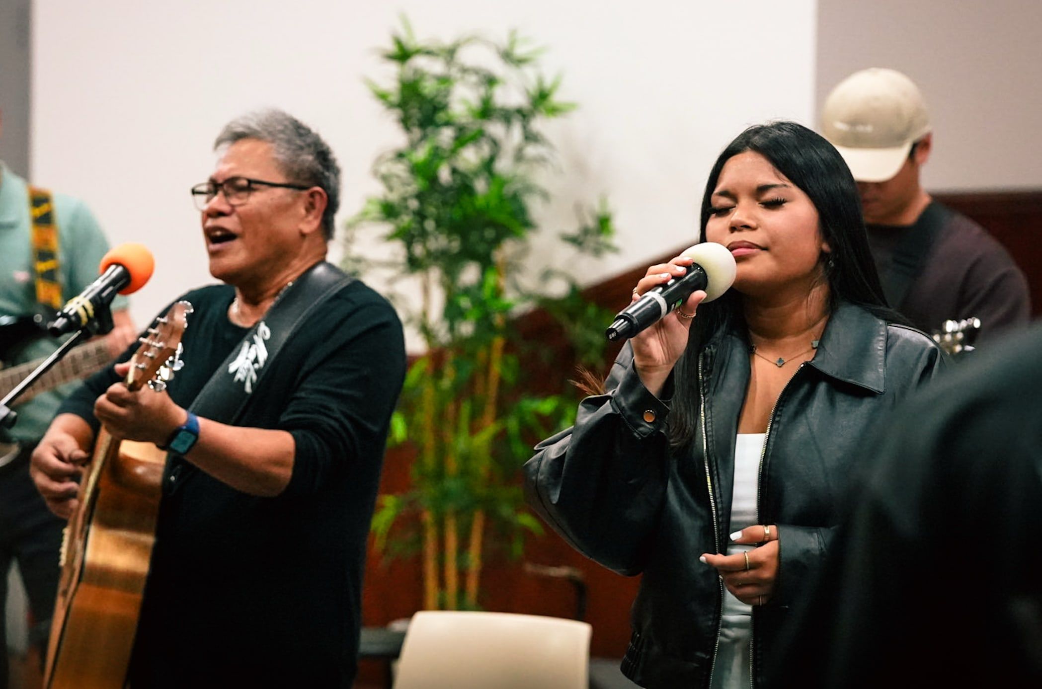 Joel Gonzales sings and plays guitar beside a young vocalist, eyes closed in worship, at CoastWIDE Church in Arundel, Gold Coast