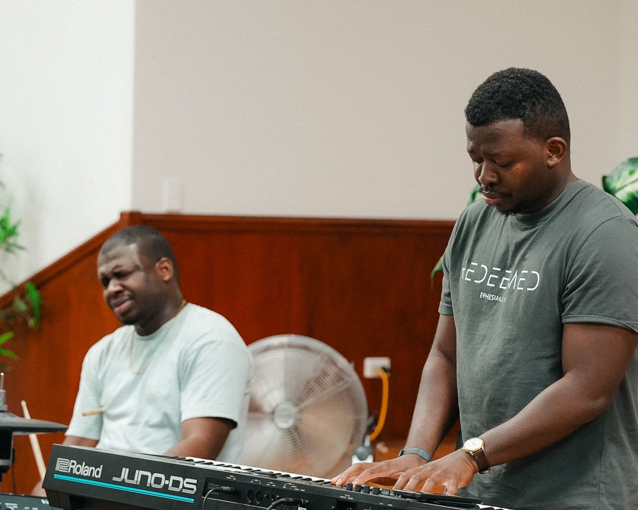 A young man plays keyboard as a drummer plays behind him during worship at CoastWIDE Church