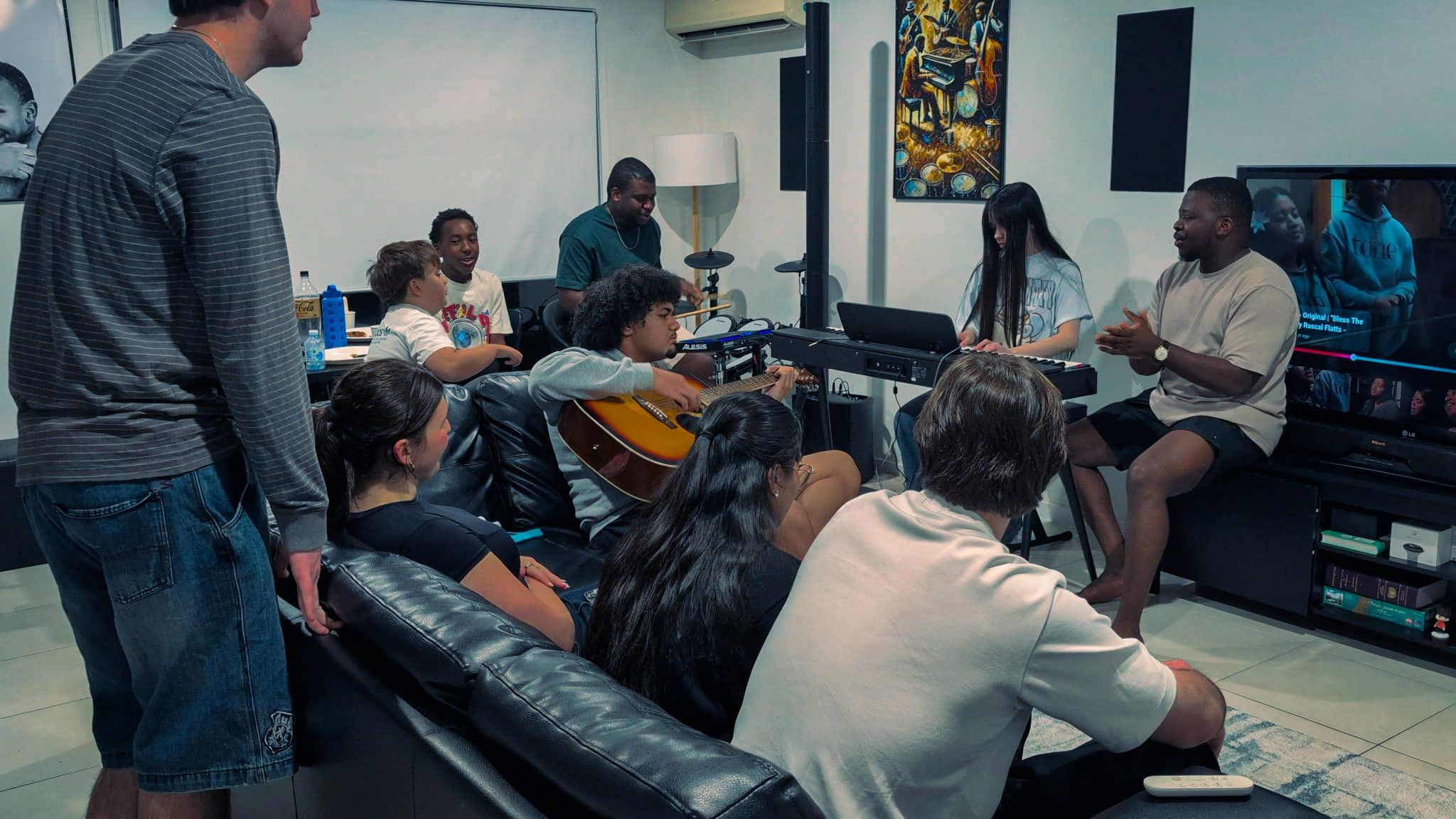Young adults relaxing on couches with a guitar and keyboard at a CoastWIDE Church Young Adults night