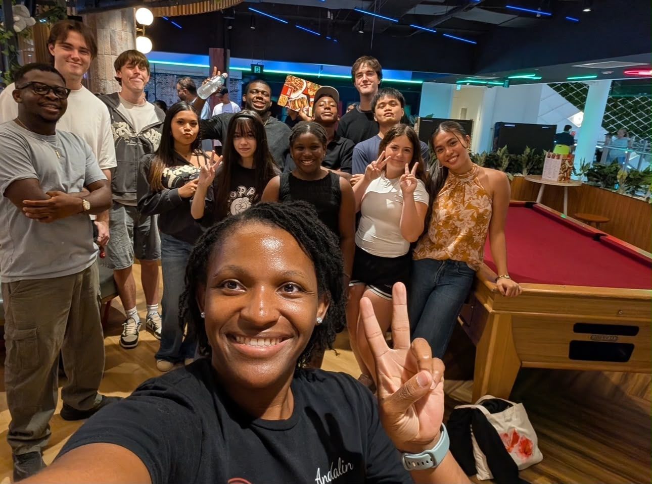 CoastWIDE Church Young Adults smiling together for a group selfie, a leader making a peace sign in front of high schoolers and twenty-somethings from many backgrounds